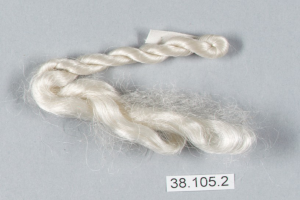 Ein Faden weißer Seide auf einer grauen Oberfläche mit einer darauf geschriebenen Zahl.