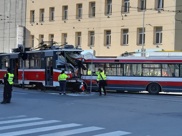 Rote und weiße Straßenbahn beteiligt an einem Straßenrandunfall mit einigen Menschen in der Nähe und einem Gebäude im Hintergrund.