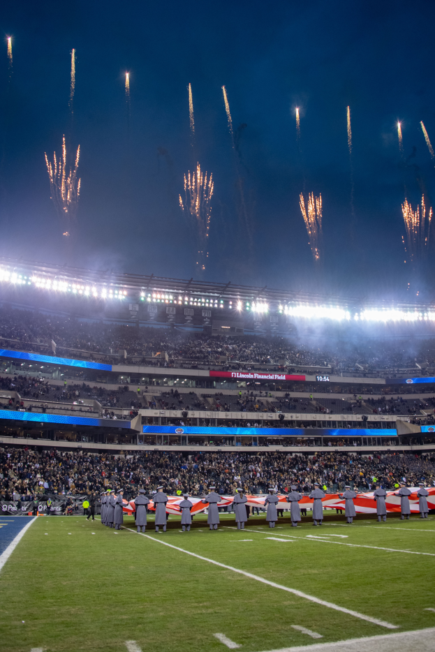 Ein Fußballstadion voller Stehplätze unter hellen Lichtern, mit Feuerwerk am Himmel darüber.