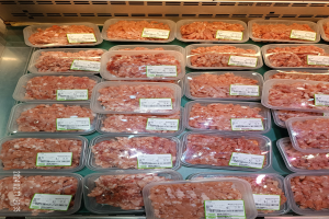 Vitrine voller verschiedener gefrorener Fleischwaren in Plastikbehältern, jeweils mit einem Preisschild versehen.
