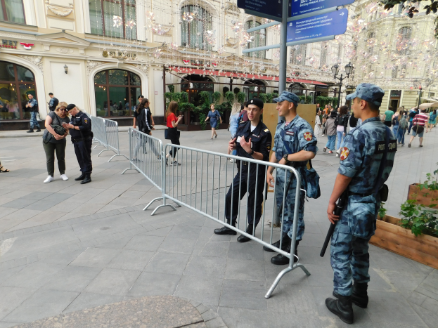 Eine Gruppe von Polizisten steht vor einer Menge, einige halten Waffen, mit Barrikaden und Texttafeln im Vordergrund und Gebäuden, Laternenmasten, Pflanzen und Bäumen im Hintergrund in Wien, Österreich während eines Anti-Terror-Einsatzes.