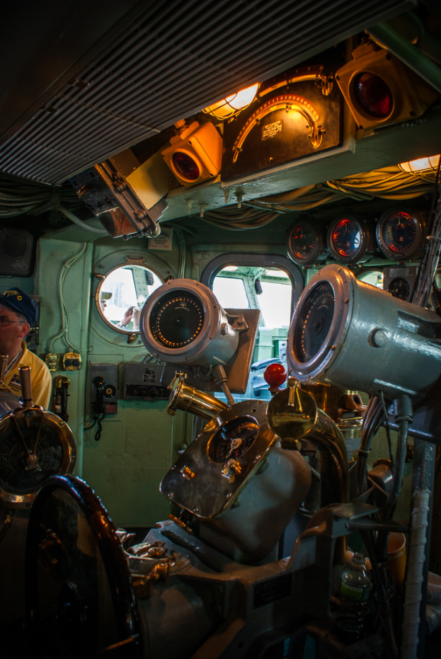 Das Innere eines Zuges mit Sitzen und verschiedenen Gegenständen; eine Person in einem gelben T-Shirt steht auf der linken Seite.