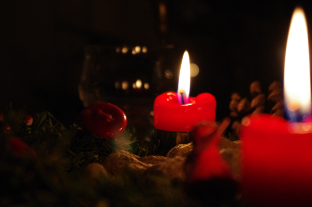 Mehrere rote Kerzen brennen und geben Flamme und Rauch ab.