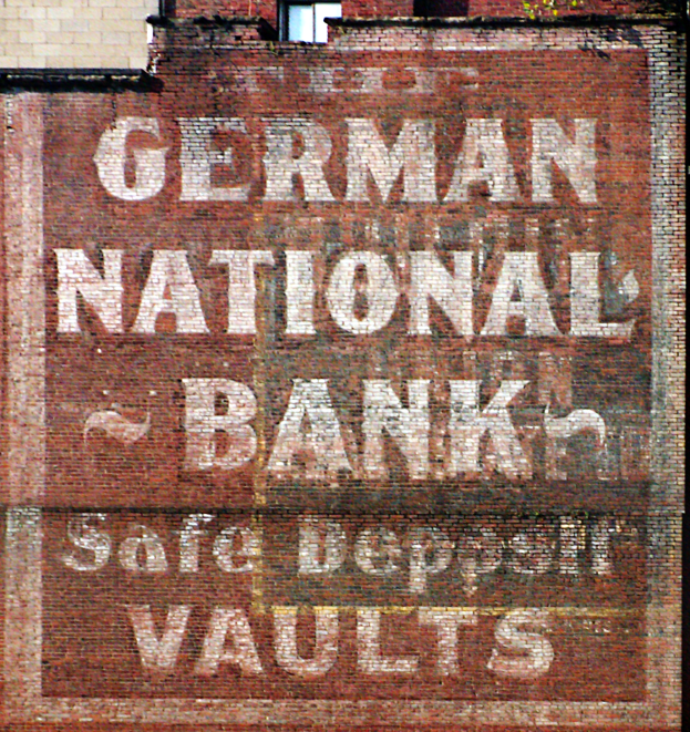 Eine Backsteinwand mit einem Schild, auf dem "Deutsche Nationalbank-Schließfächer" steht, und einem Fenster oben.