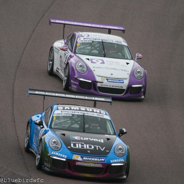 Zwei Autos auf einer Straße außerhalb einer Stadt, mit Text in der unteren linken Ecke.