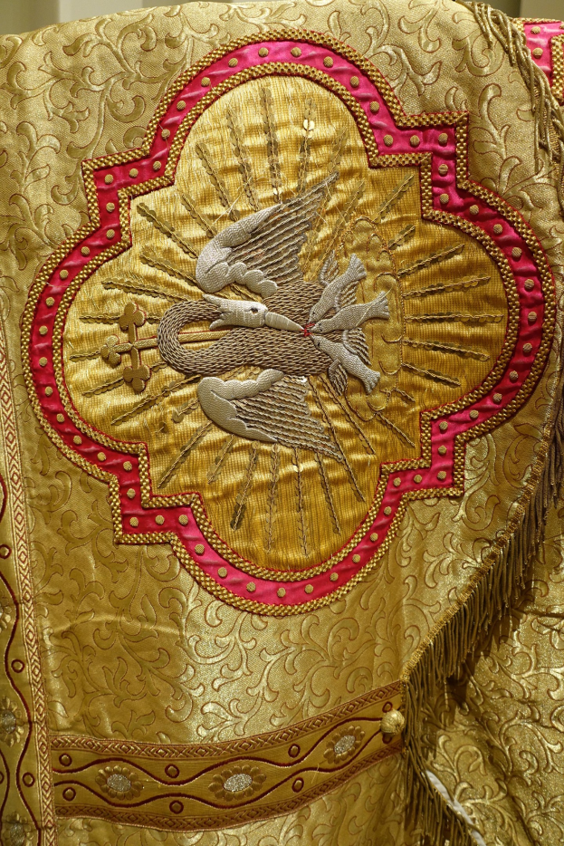 Nahaufnahme eines Priestergewandes mit aufwendiger Gold- und Rotstickerei und einem luxuriösen, königlichen Design an einer Wand.