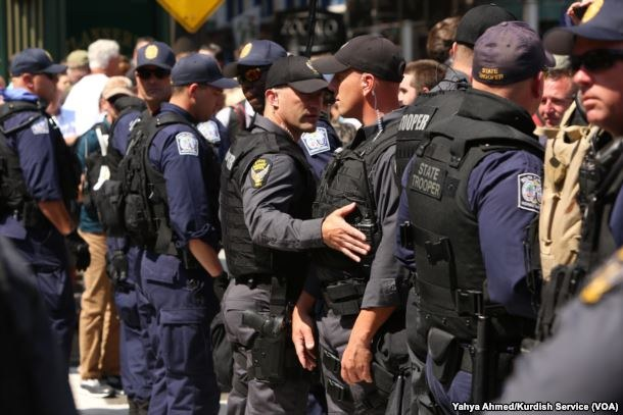 Gruppe von Polizisten in Uniform auf einer Straße mit Gebäuden und Schildern im Hintergrund.