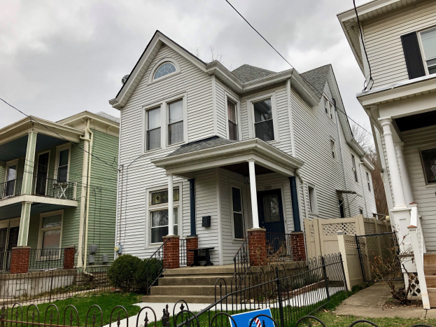 Eine Reihe von Häusern mit verschiedenen architektonischen Merkmalen, umgeben von einem Metallzaun, Grünfläche und einem bewölkten Himmel, mit einem Vermietungsschild unten, das die Liste ID 29058910 und die Adresse 5901 S Elmwood Ave, Chicago 60618 anzeigt.