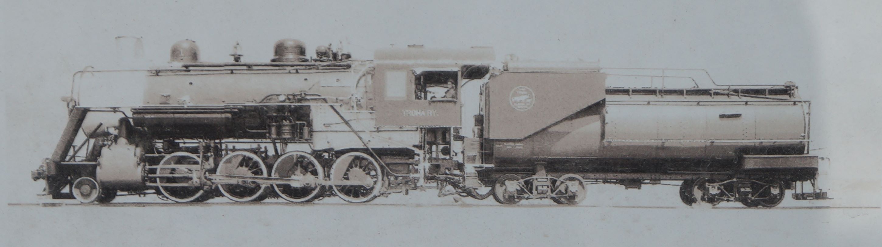 Altes Schwarz-Weiß-Foto einer großen, alten Dampflokomotive mit Schornstein, Scheinwerfern, Kühlergrill, Rädern und einem Waggon auf Eisenbahnschienen.