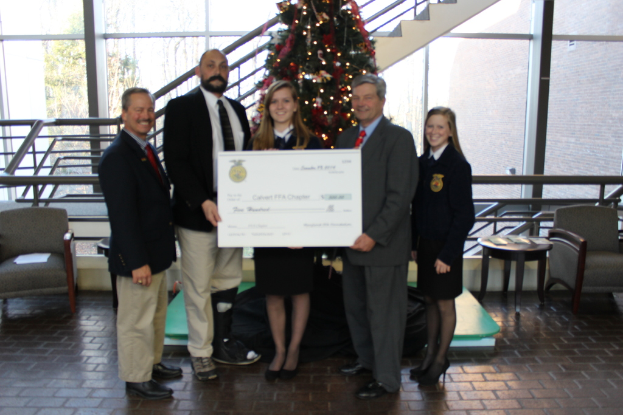 Eine Gruppe von Menschen, die Zertifikate halten und vor einem Weihnachtsbaum, einer Treppe, einem Sofa, einem Tisch, einem Glas und Bäumen stehen.