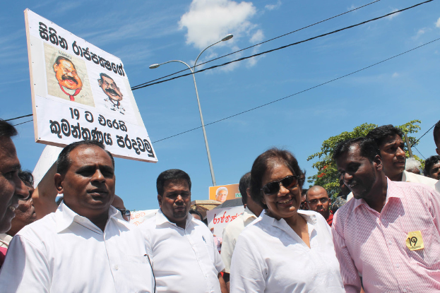 Männer stehen und protestieren, indem sie Schilder halten, mit Stangen, Drähten, Bäumen und dem Himmel im Hintergrund.