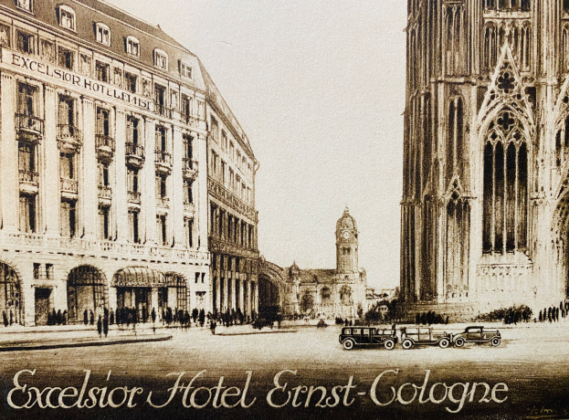 Ein Plakat des Excelsior Hotel Ernst Köln mit Fahrzeugen auf der Straße, Menschen, die gehen, und Gebäuden im Hintergrund, unter einem sichtbaren Himmel, mit Text unten.