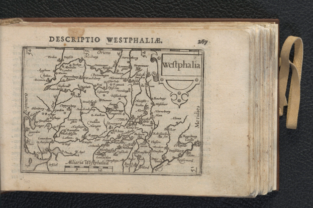 Ein aufgeschlagenes Buch mit einer detaillierten Karte von Westfalen auf einer schwarzen Oberfläche.