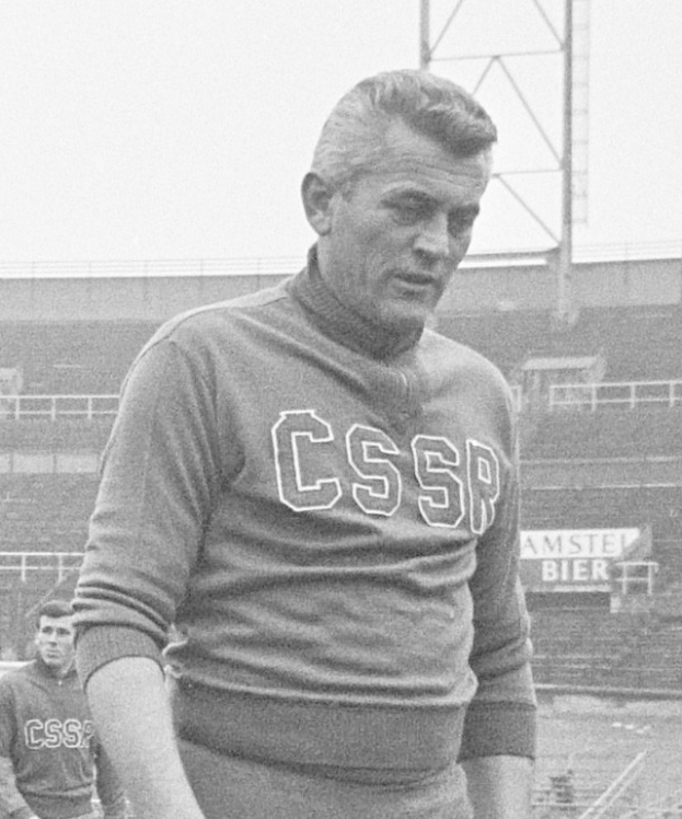 Ein Schwarz-Weiß-Foto eines Mannes, der auf einem Feld steht und ein T-Shirt mit Text trägt, vor einem Stadion und einer Werbetafel, bei dem es sich mutmaßlich um den Fußballspieler César Azpilicueta handelt.