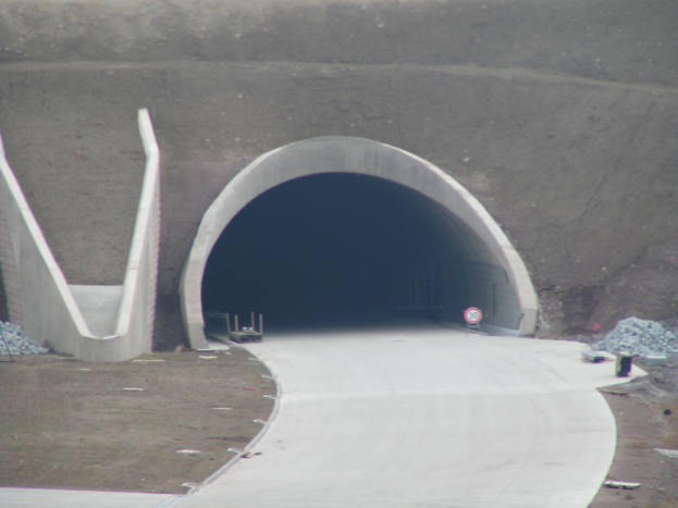 Ein Tunnel mit einem Schild in der Mitte, eine Straße unten und verschiedene Objekte auf der rechten Seite.