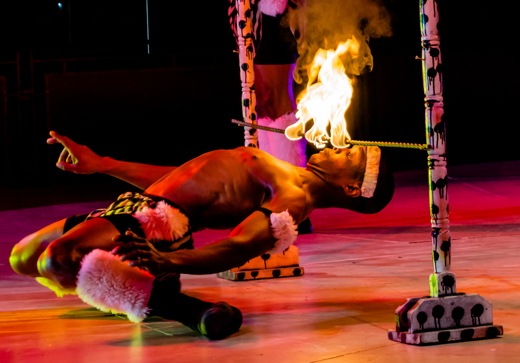 Eine Person schaut auf ein Feuer, das auf einer Stange an Pfählen brennt.