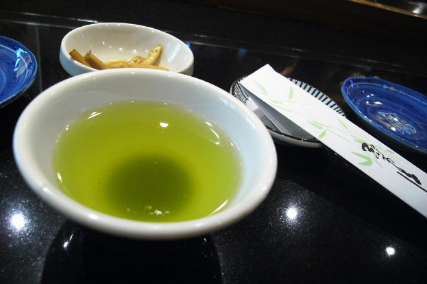 Ein schwarzes Tablett mit einem Teller mit Essen, einer Schüssel Suppe und einem unbekannten Gegenstand.