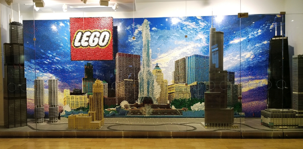 Eine Sammlung von Lego-Kreationen, die auf einem Boden mit einer Wand im Hintergrund angezeigt werden.