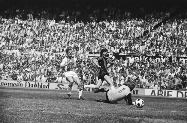 Schwarzes und weißes Foto von Männern, die auf einem Feld Fussball spielen, mit Zuschauern im Hintergrund und einem Banner "Bundesliga 1978-79 Ajax 1-1 Hannover 96".