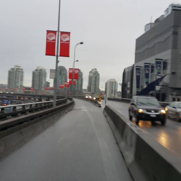 Eine fast leere Straße mit Gebäuden im Hintergrund und ein paar Pfählen in der linken Ecke.