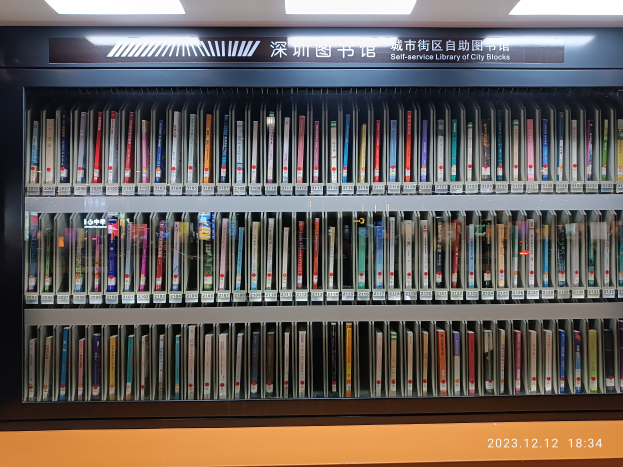 Eine gut beleuchtete Bibliothek mit zahlreichen Büchern auf Regalen, ein Textschild und ein Wasserzeichen unten, das wie eine Selbstbedienungsbibliothek von Stadtblöcken aussieht.