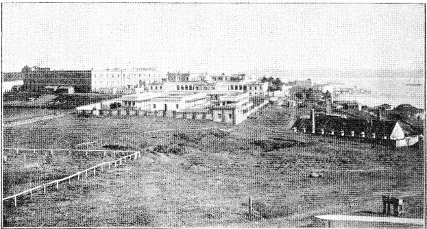 Ein Schwarz-Weiß-Foto einer Stadtlandschaft mit Gebäuden, Pfählen, Bäumen und Wasser sowie dem Text "New York State Penitentiary" unten.