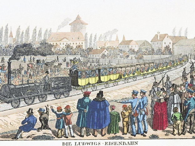 Gruppe von Menschen um ein stehendes Zug auf Schienen versammelt, mit einigen Passagieren im Zug und anderen stehend, vor Gebäuden und Bäumen im Hintergrund, mit Text unten lesend "Ludwigs-Eisenbahn, die erste Bahnstation in Deutschland".