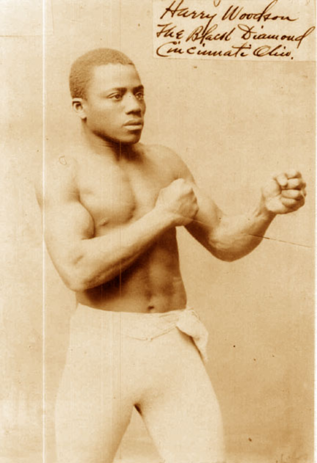 Ein Mann in einem Boxring mit Handschuhen und Shorts, der entschlossen in die Ferne blickt.