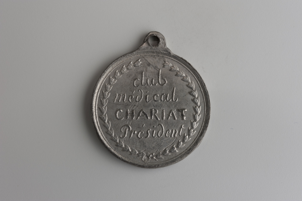 Eine Silbermedaille mit der Aufschrift 'Club Medical Charity President' auf einem weißen Hintergrund.