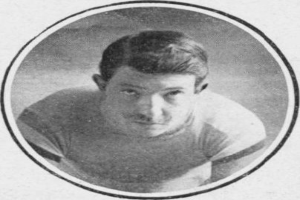 Schwarzes und weißes Foto eines Mannes in einem Fußballtrikot mit ernstem Gesichtsausdruck, dunklem Kurzhaarschnitt und konzentrierten Augen.