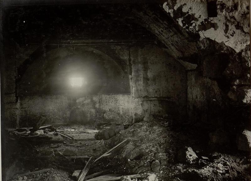 Ein Schwarz-Weiß-Foto eines einstürzenden Tunnels in den Berliner Mauerruinen, mit Schutt auf dem Boden und einem Licht am Ende.