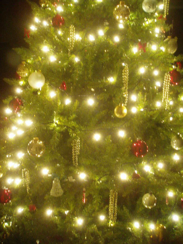 Ein Weihnachtsbaum geschmückt mit Lichtern, Kugeln und verschiedenen Dekorationen.