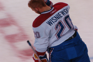 Ein Hockey-Spieler im 'Wisniewski'-Trikot steht auf dem Eis und hält einen Hockey-Schläger in der Hand.