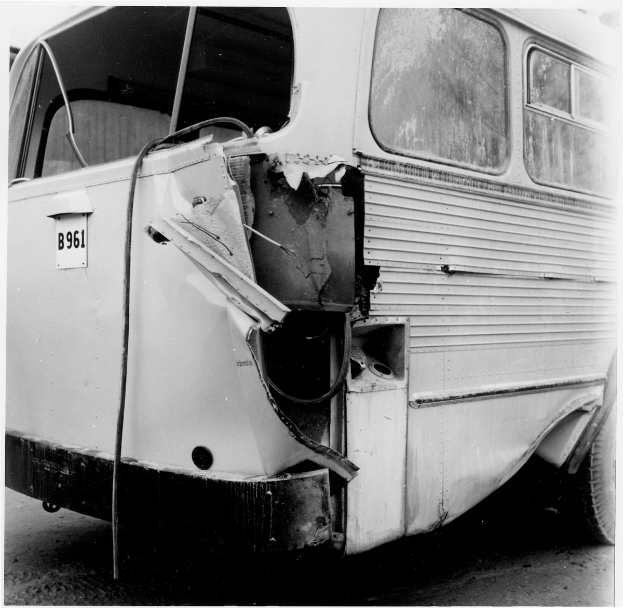 Schwarz-weißes Foto eines Busses mit schwerer Frontschädigung durch einen Autounfall auf der Straße.