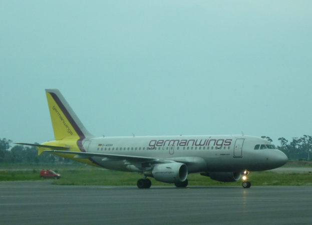 Ein Airbus A320-200 der Germanwings auf dem Rollfeld am Frankfurter Airport, mit einem Fahrzeug auf der linken Seite, Gras, Bäumen und dem Himmel im Hintergrund.