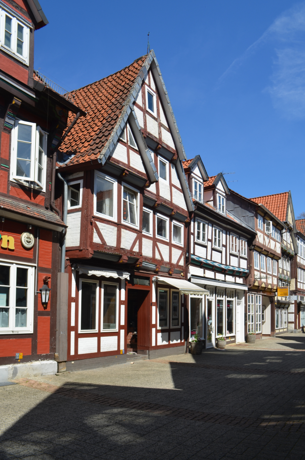 Ein Kopfsteinpflasterweg in Heidelbergs Altstadt mit Gebäuden im Vordergrund, einem klaren blauen Himmel im Hintergrund und einer Straßenlaterne auf der linken Seite.
