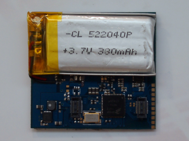 Nahaufnahme einer Mobiltelefonbatterie auf einer Leiterplatte mit gedrucktem Text, die auf einer weißen Oberfläche liegt.