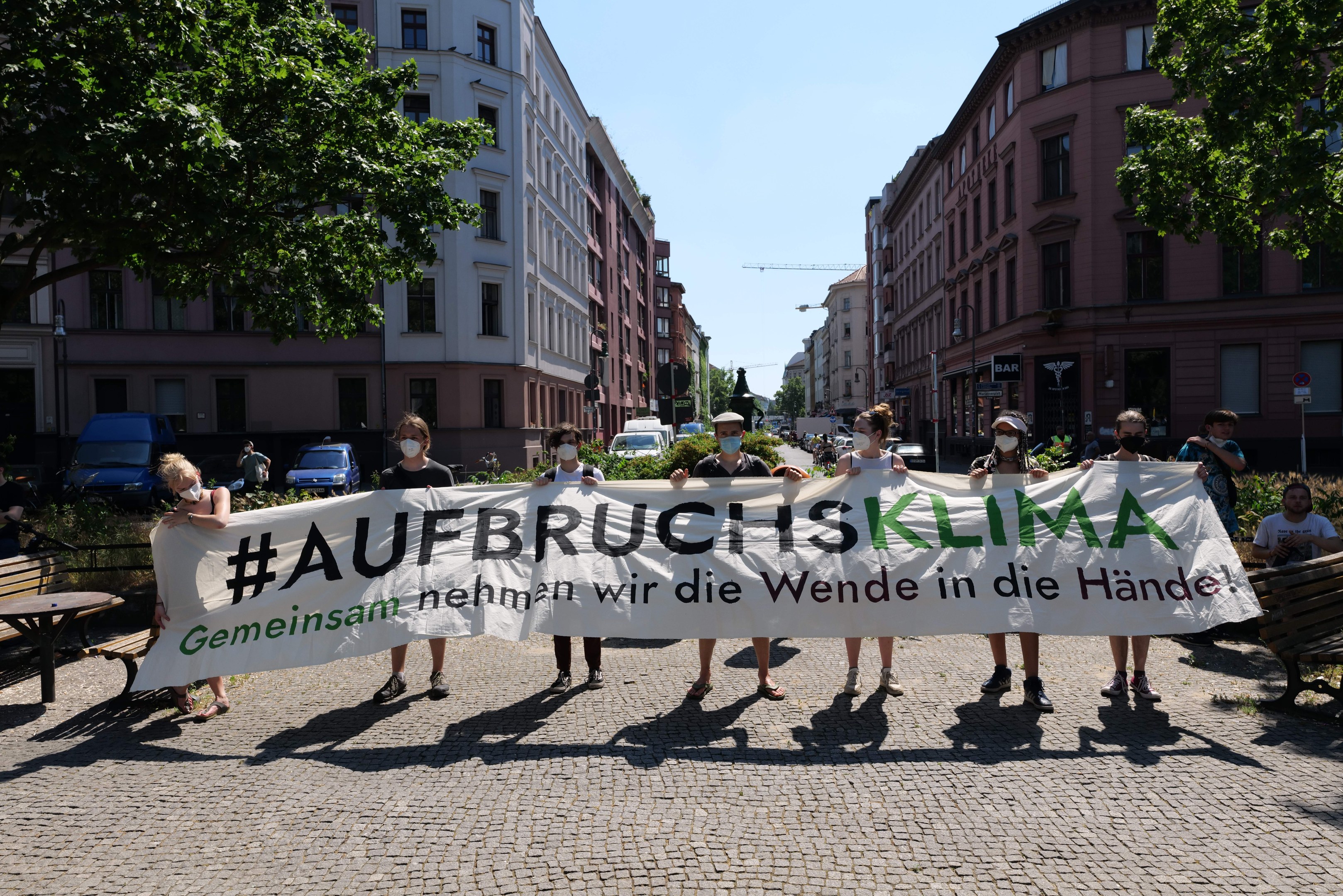 Gruppe von Menschen mit Masken, die ein Banner mit der Aufschrift 'Aufbruchsklima' während einer Klimaprotest in Berlin halten