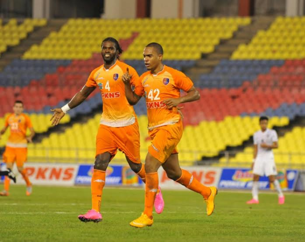 Eine Gruppe von Männern, die auf einem Rasenfeld Fußball spielen, tragen die Farben der Indian Super League 2019-20, mit Werbetafeln, Stühlen, Säulen und Wänden im Hintergrund.