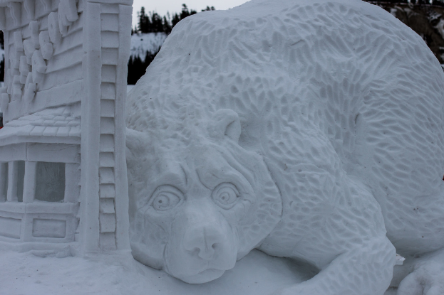Schneekunst im Vordergrund mit ein paar Bäumen und dem Himmel im Hintergrund.
