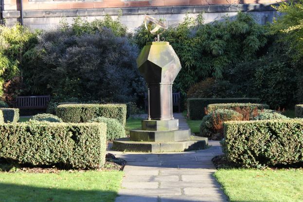 Eine Parkszene mit verschiedenen Pflanzen, Bäumen und einem einzelnen Pfahl.