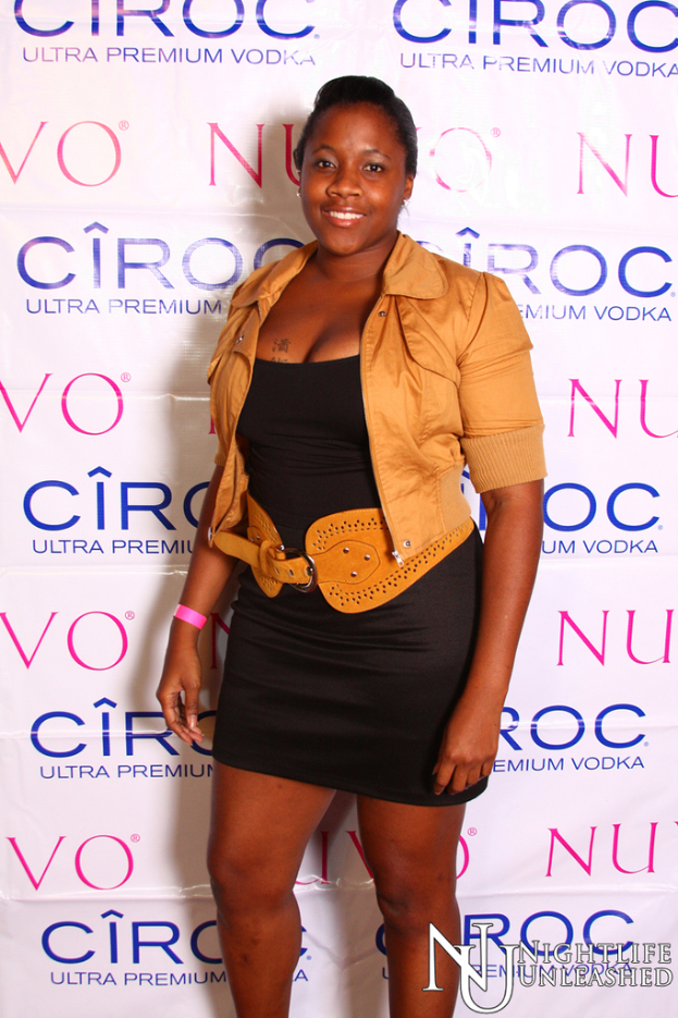 Eine Frau steht lachend vor einer Wand mit einem Sponsorennamen darauf.