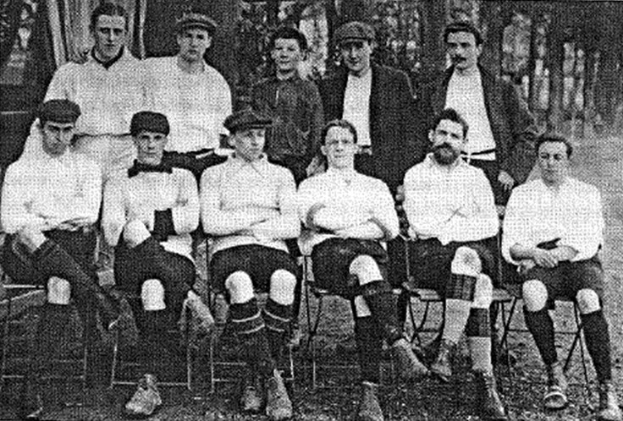 Schwarze und weiße Mannschaftsfoto von West Bromwich Albion Football Club aus dem Jahr 1918, mit sitzenden und stehenden Spielern und Bäumen im Hintergrund.